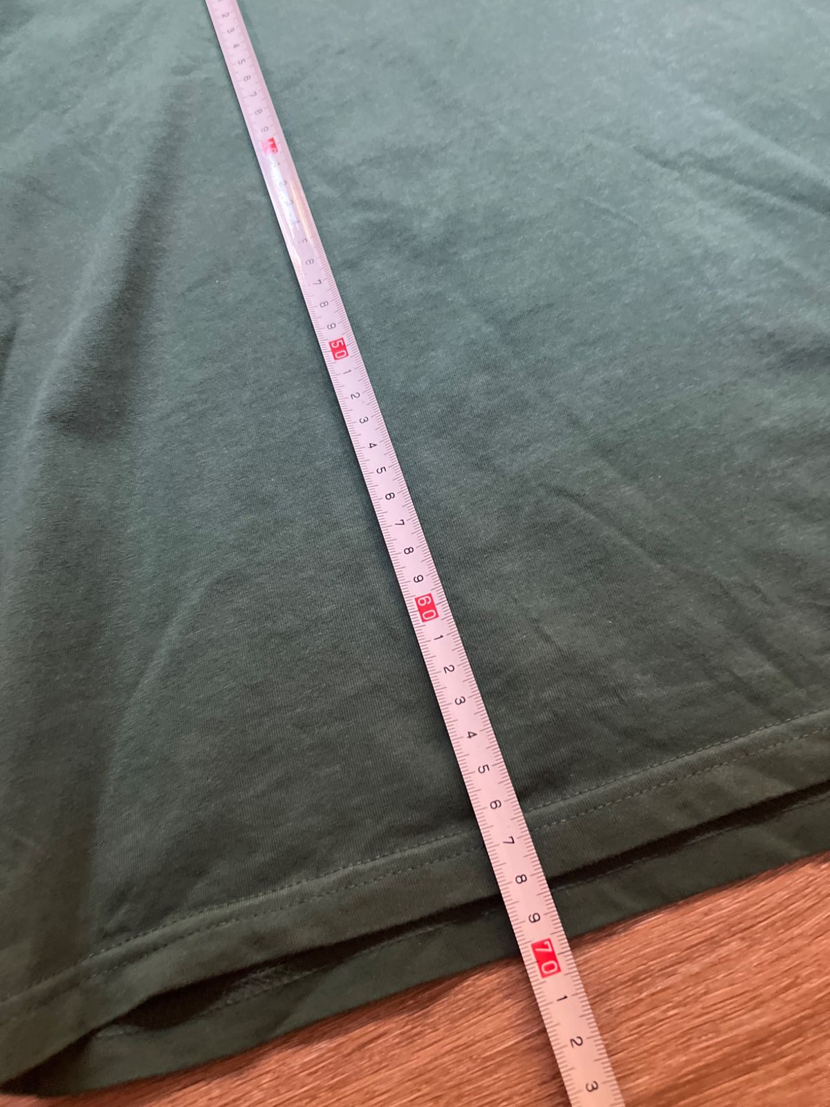 A tape measure measuring the length of the green Carhartt T-shirt